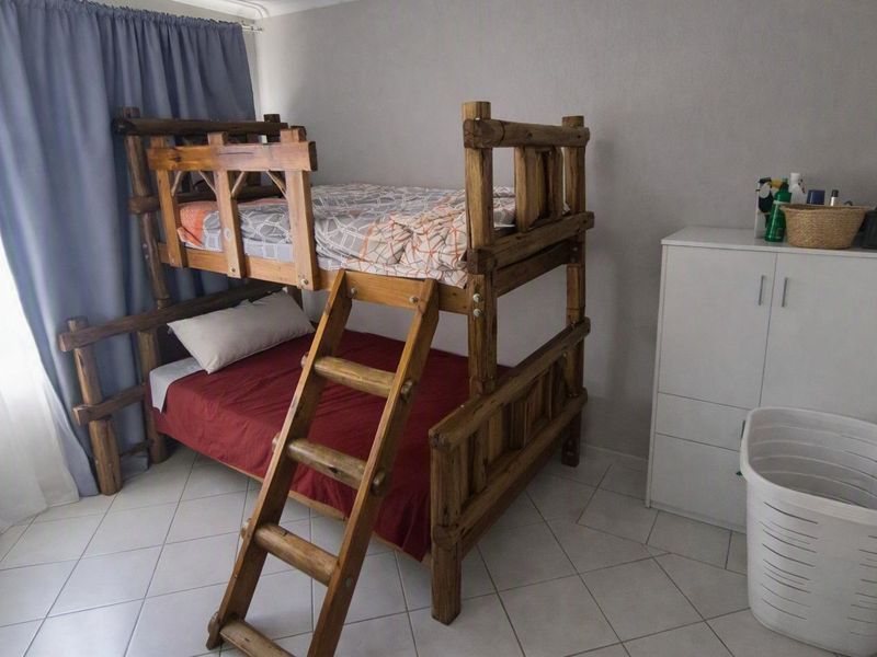 A functional bedroom featuring neutral wall finishes and tiled flooring, providing a clean and simple space.