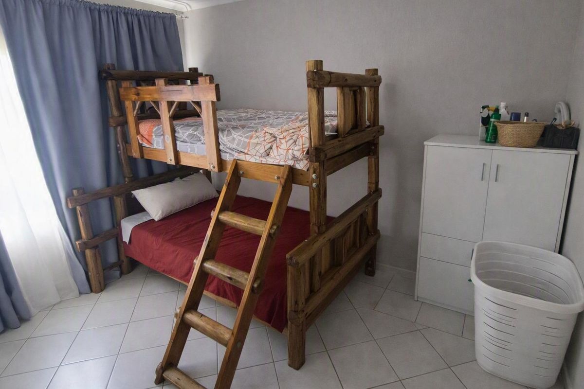 A functional bedroom featuring neutral wall finishes and tiled flooring, providing a clean and simple space.