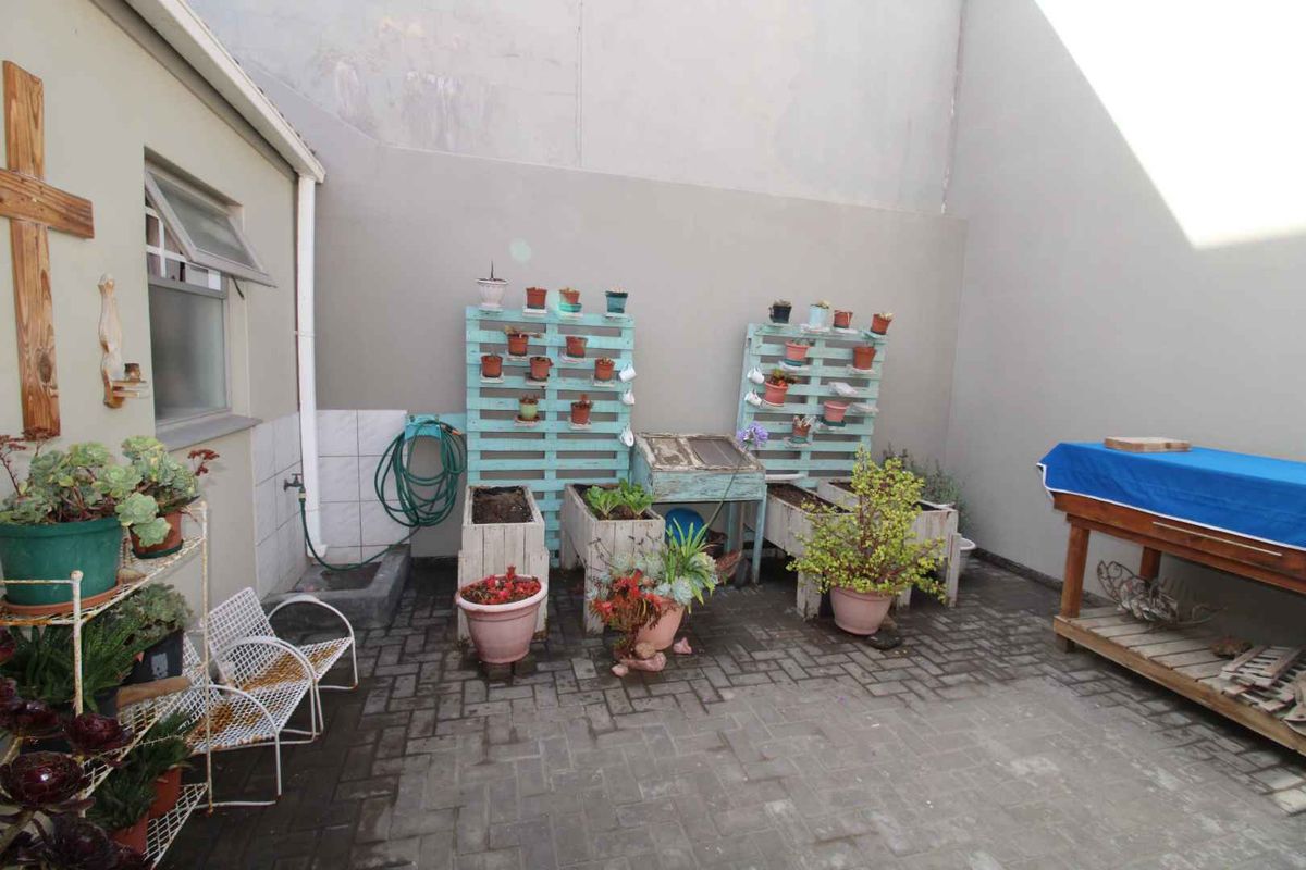 A private paved courtyard area featuring high boundary walls, an outdoor water tap, and a functional utility space.