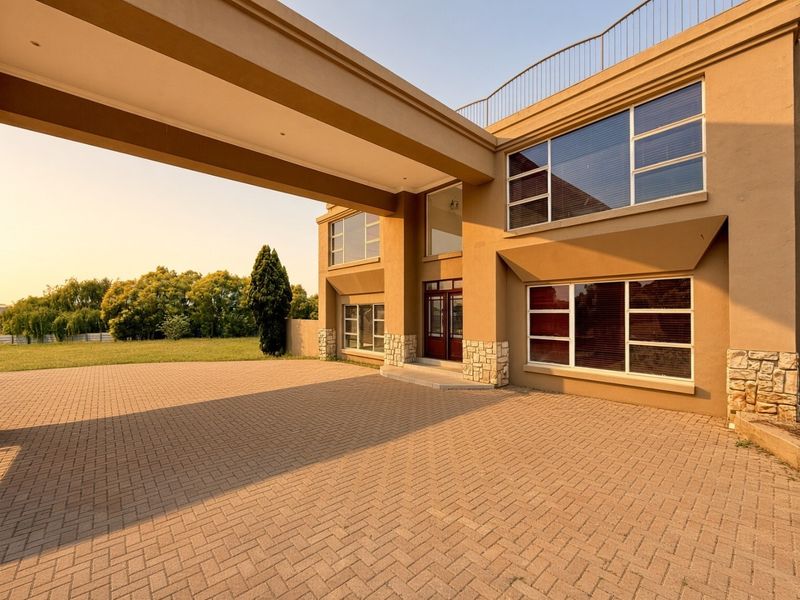 A modern two-story house exterior featuring a paved driveway, a covered porte-cochere, stone cladding accents, and large windows.