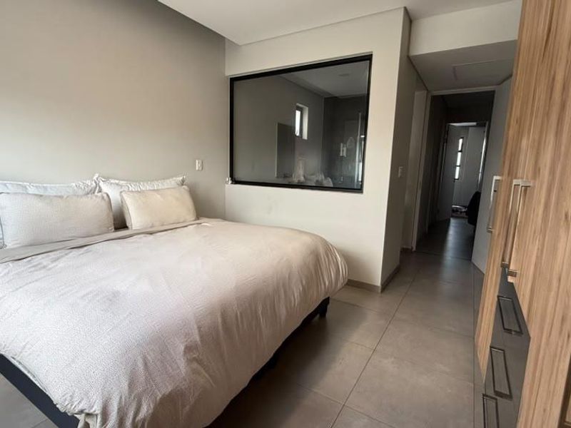 Modern bedroom featuring tiled flooring, a built-in wardrobe, and a unique internal glass partition looking into the adjacent bathroom area.
