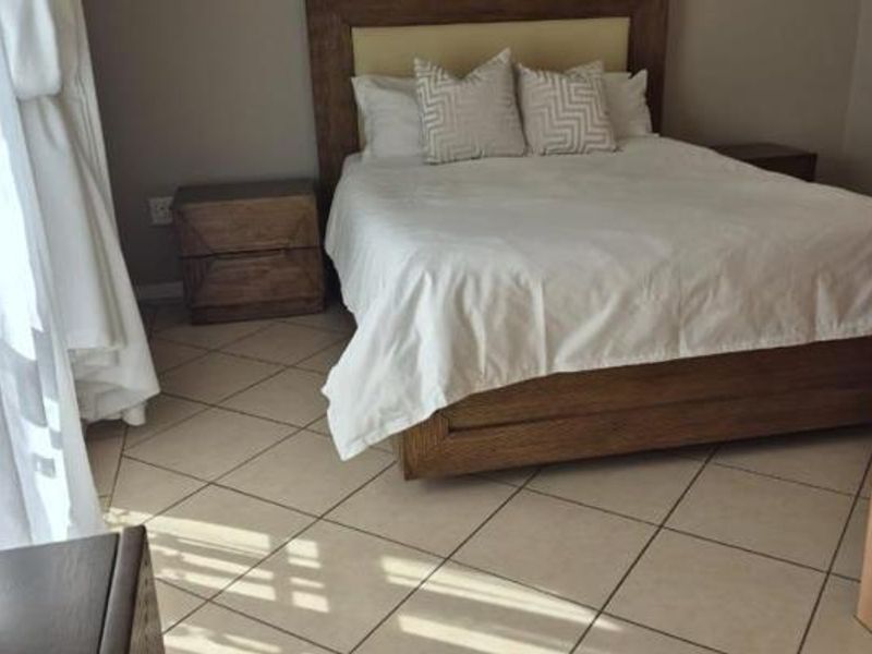 A bedroom featuring tiled flooring and a built-in headboard, offering a functional space with neutral finishes.