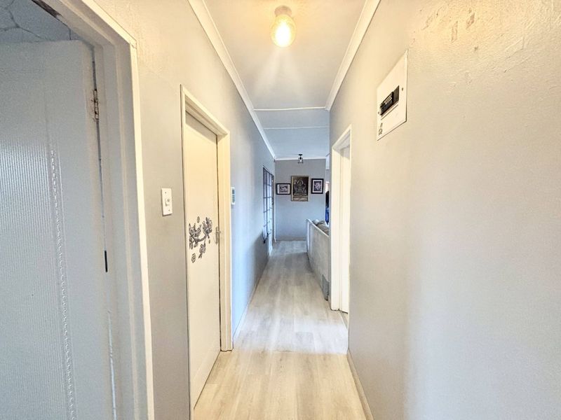 A functional hallway featuring light-toned laminate flooring, neutral wall finishes, and access to multiple rooms within the townhouse.
