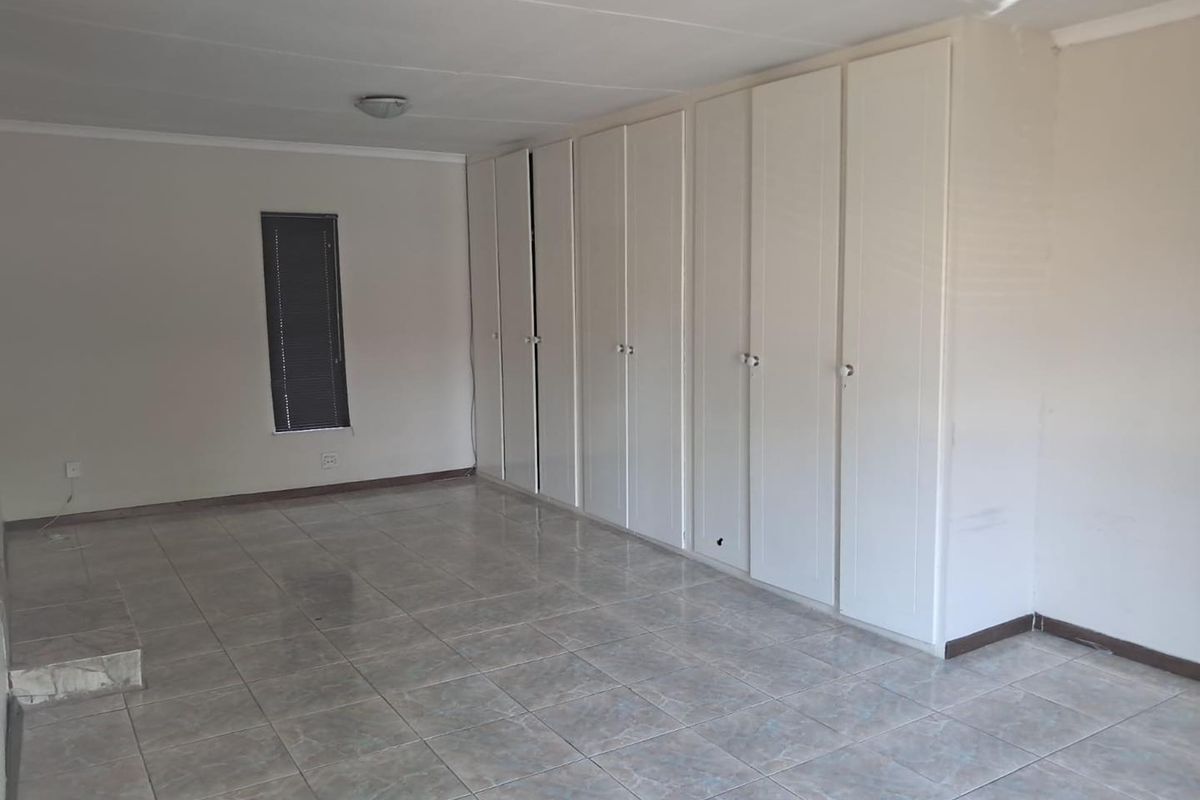 A spacious bedroom featuring neutral tiled flooring and extensive built-in floor-to-ceiling cabinetry providing ample storage space.