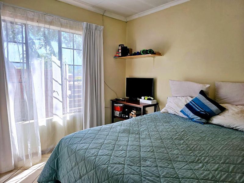 A bedroom featuring tiled flooring and a window with security bars, requiring cosmetic updates to the wall and ceiling finishes.