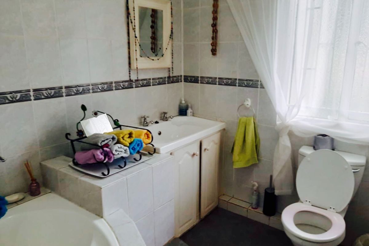 A functional bathroom featuring a built-in vanity with integrated basin, tiled walls, and a standard toilet suite.