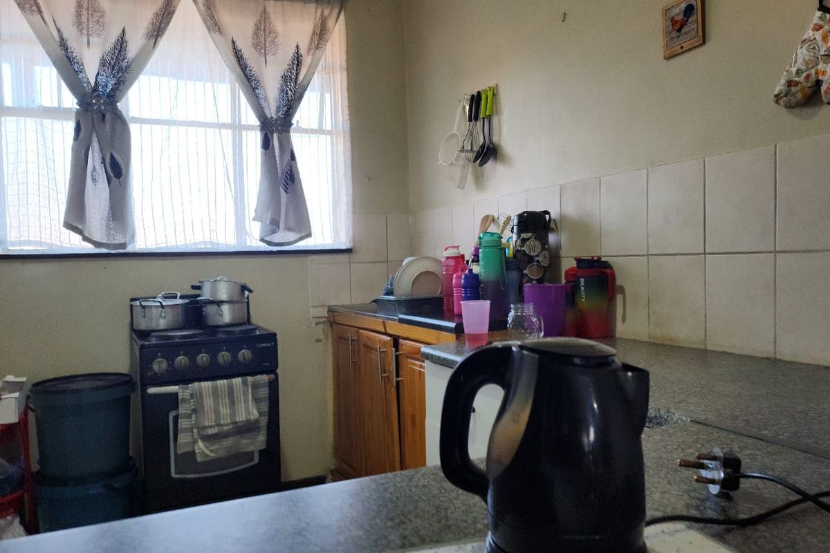 A functional kitchen featuring built-in wooden cabinetry, tiled splashbacks, and a freestanding stove, offering a practical layout for daily meal preparation.
