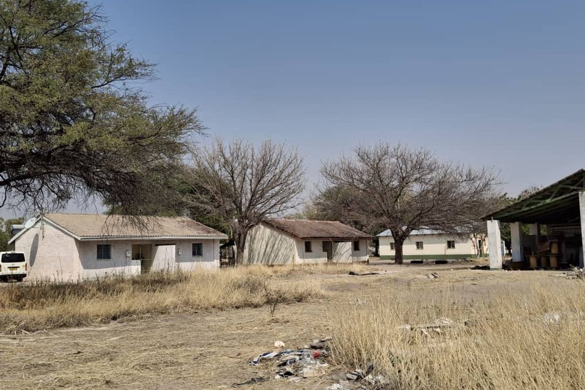 A view of multiple detached single-story structures on a large plot, featuring basic masonry construction and metal roofing in a rural setting.