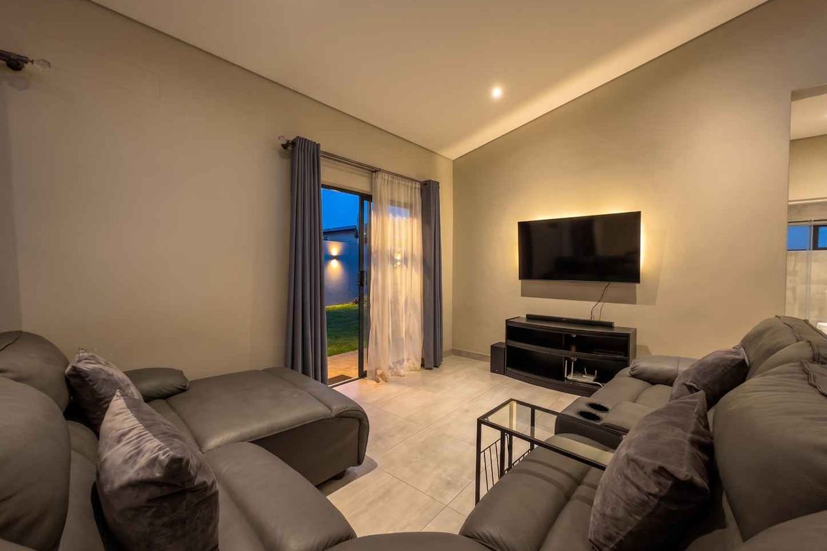 A modern living room featuring tiled floors, recessed lighting, and a sliding glass door providing direct access to the outdoor area.