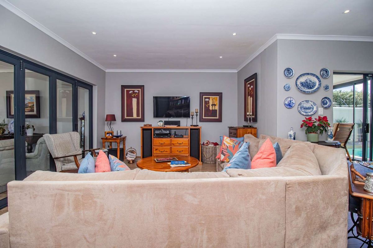 A comfortable living room featuring recessed ceiling lighting, neutral wall tones, and large glass sliding doors that provide access to the outdoor area.