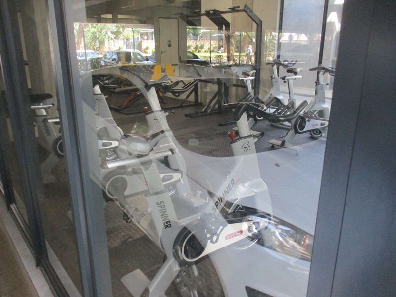 A communal gym facility featuring rubberized flooring and large glass windows, providing a view into the exercise area.