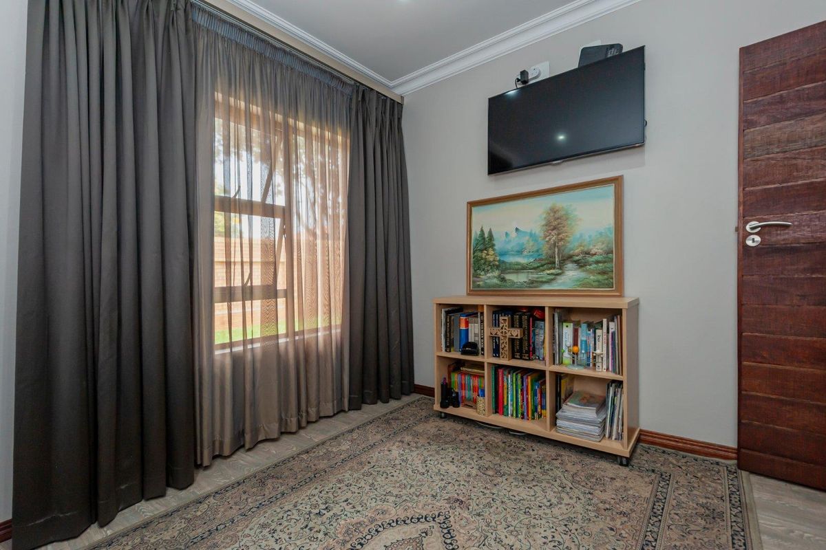 A well-maintained bedroom featuring neutral wall tones, crown molding, and a solid timber door.