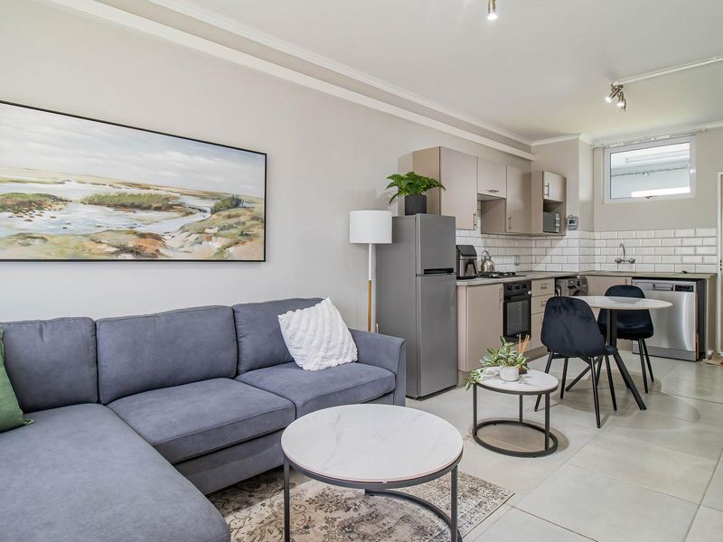 Modern open-plan living area featuring a well-appointed kitchen with subway tile backsplash, built-in cabinetry, and sleek tiled flooring throughout.