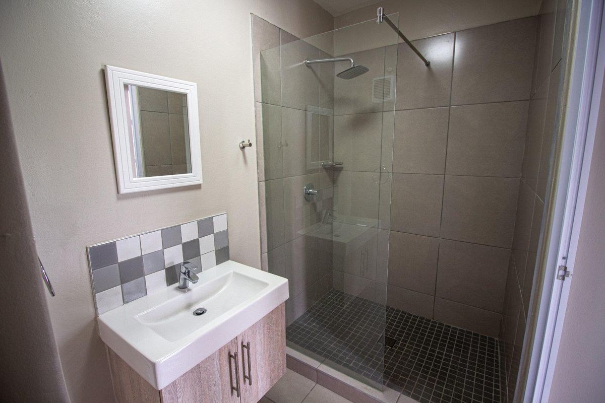 Modern bathroom featuring a walk-in shower with glass enclosure, tiled walls, and a vanity basin with storage cabinetry.