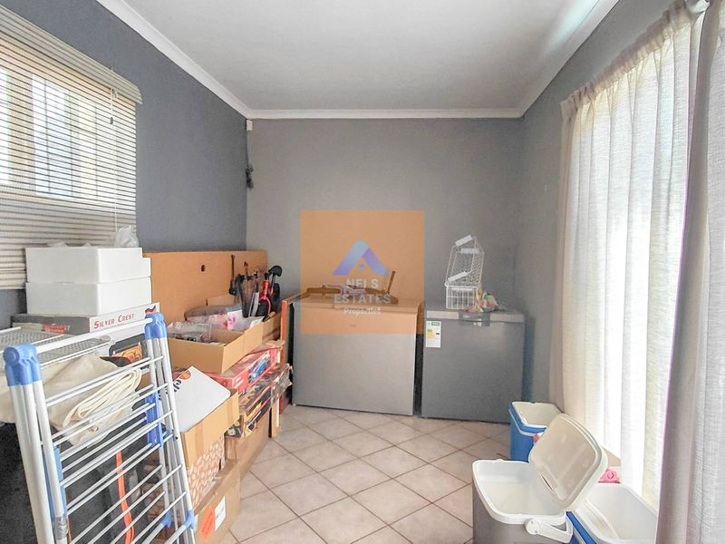 A functional utility space featuring tiled flooring and window treatments, suitable for storage or laundry purposes.