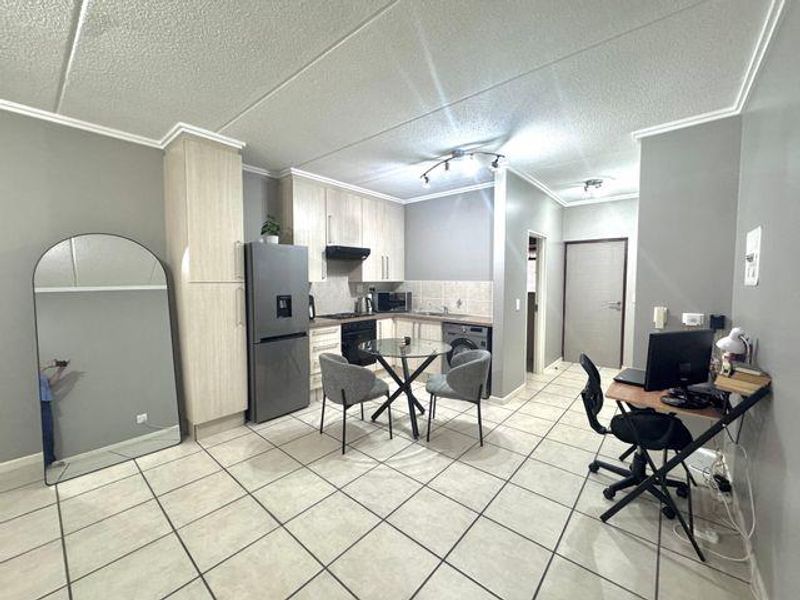 Open-plan kitchen and living area featuring light wood cabinetry, tiled flooring, and integrated appliances, providing a functional and versatile living space.