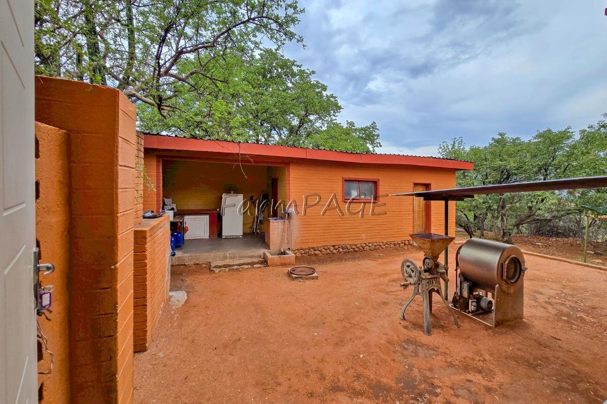 Exterior view of a rustic lodge outbuilding featuring a covered patio area, brick construction, and surrounding natural landscape.