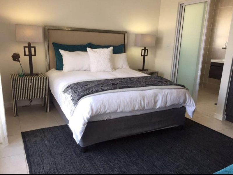 A well-maintained bedroom featuring tiled flooring and direct access to an en-suite bathroom through a sliding door.