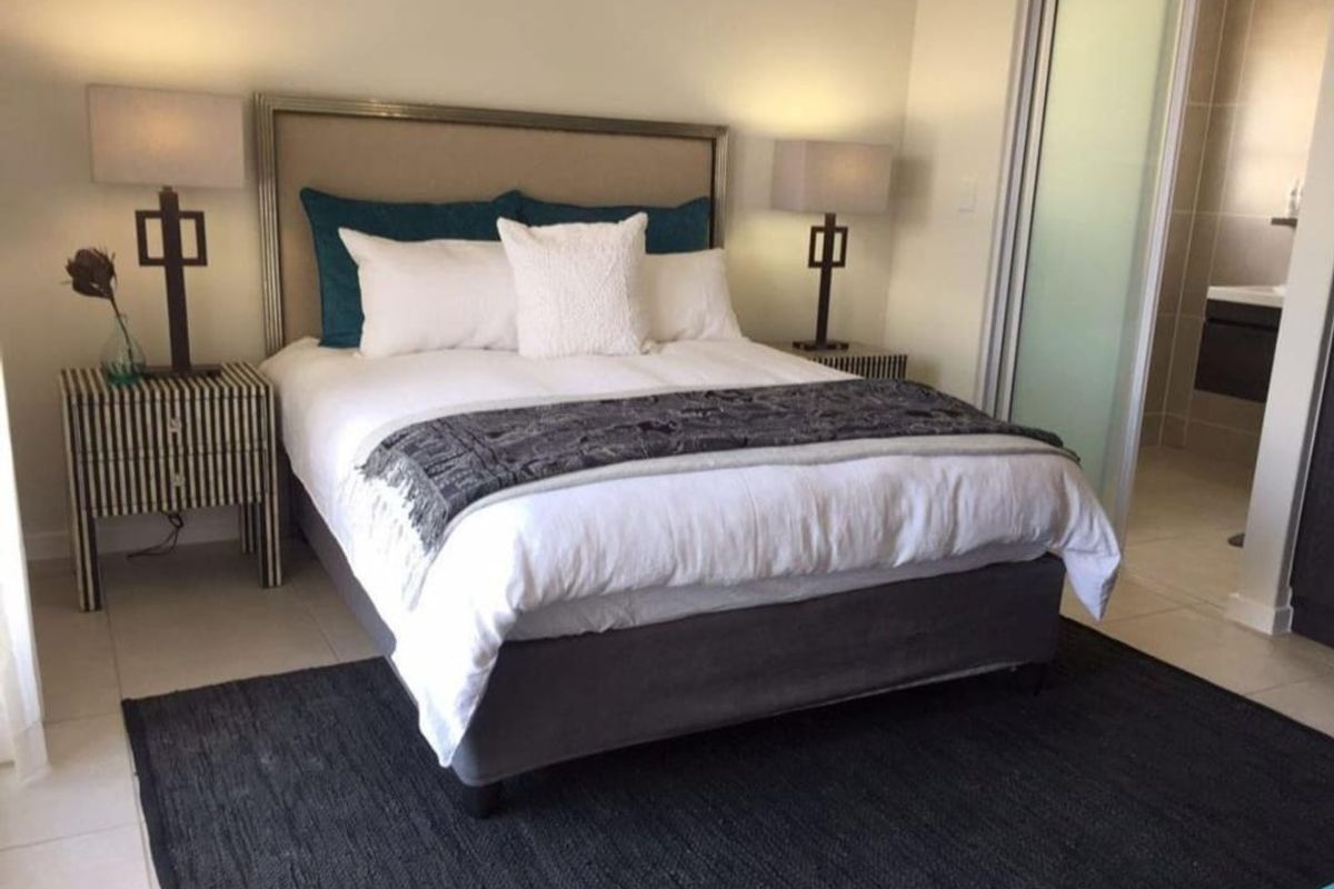 A well-maintained bedroom featuring tiled flooring and direct access to an en-suite bathroom through a sliding door.
