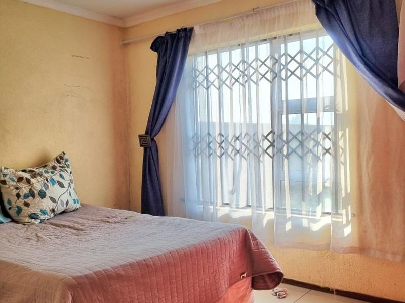 A bedroom featuring tiled flooring and a window fitted with a security gate, requiring minor cosmetic updates to the wall finishes.