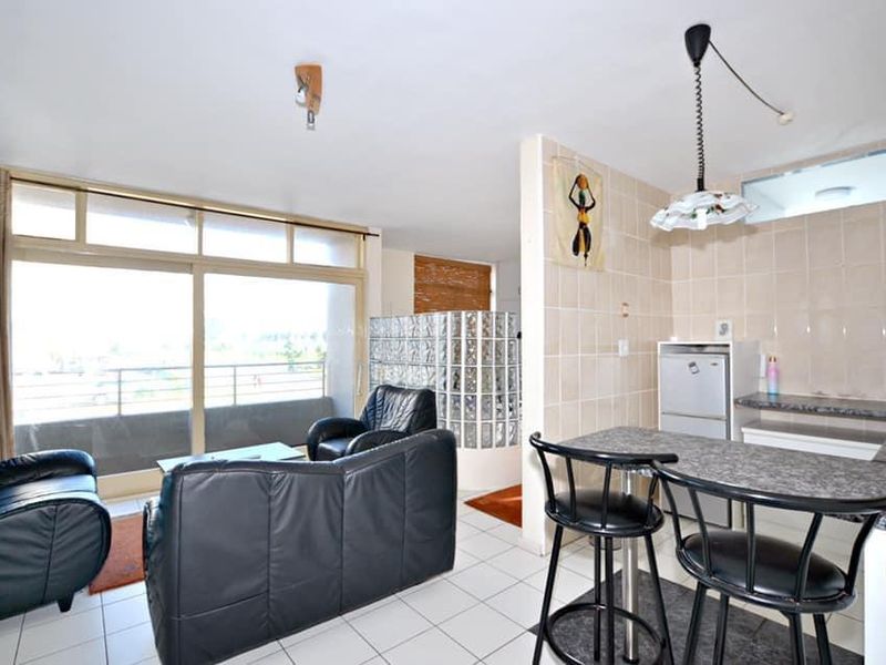 Open-plan living and kitchen area featuring a glass block partition, breakfast bar, and direct access to a balcony through sliding glass doors.