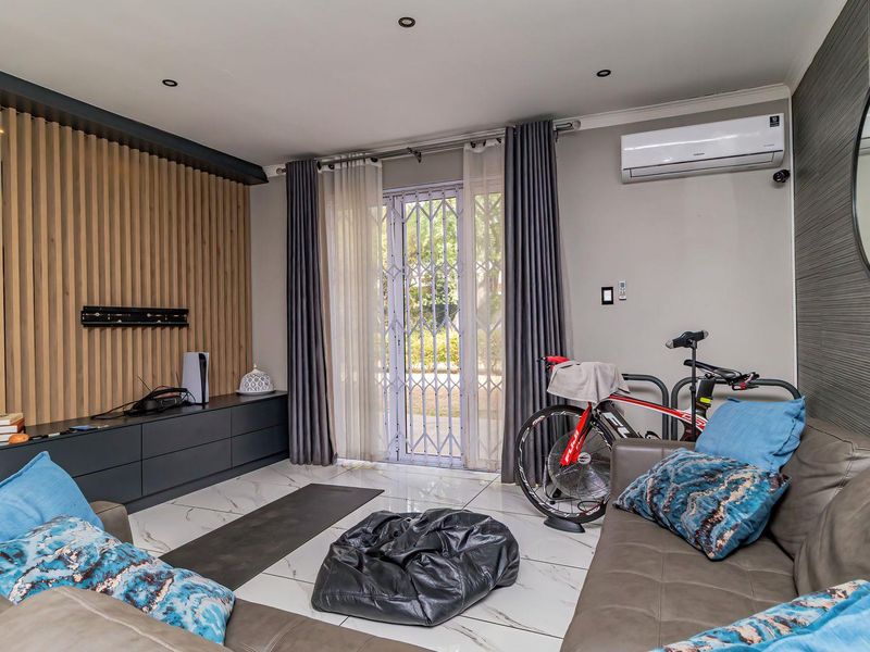 Modern living room featuring a timber slat feature wall, built-in cabinetry, tiled flooring, and a split-system air conditioner with access to an outdoor area.