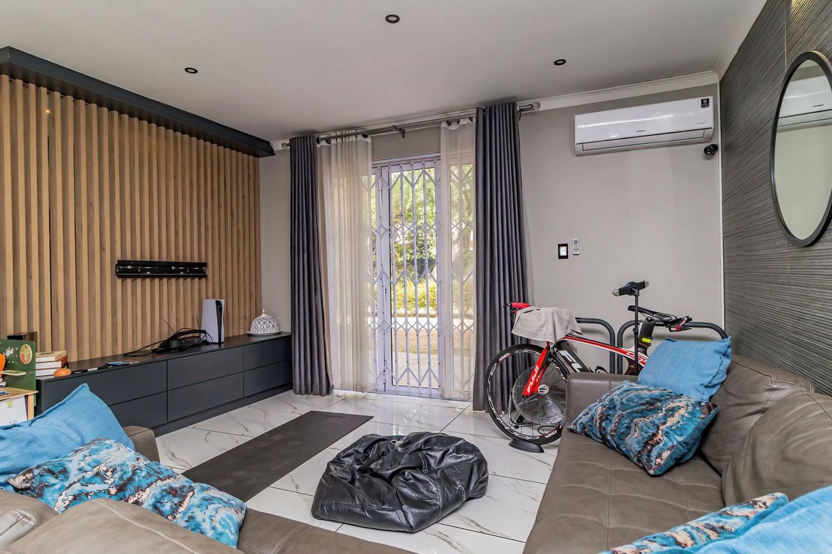 Modern living room featuring a timber slat feature wall, built-in cabinetry, tiled flooring, and a split-system air conditioner with access to an outdoor area.