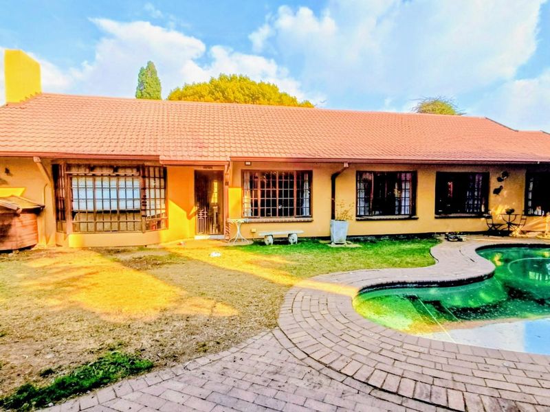 Rear view of the house featuring a swimming pool, brick paved surround, and a tiled roof with multiple bay windows.