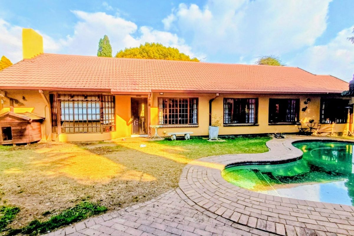Rear view of the house featuring a swimming pool, brick paved surround, and a tiled roof with multiple bay windows.