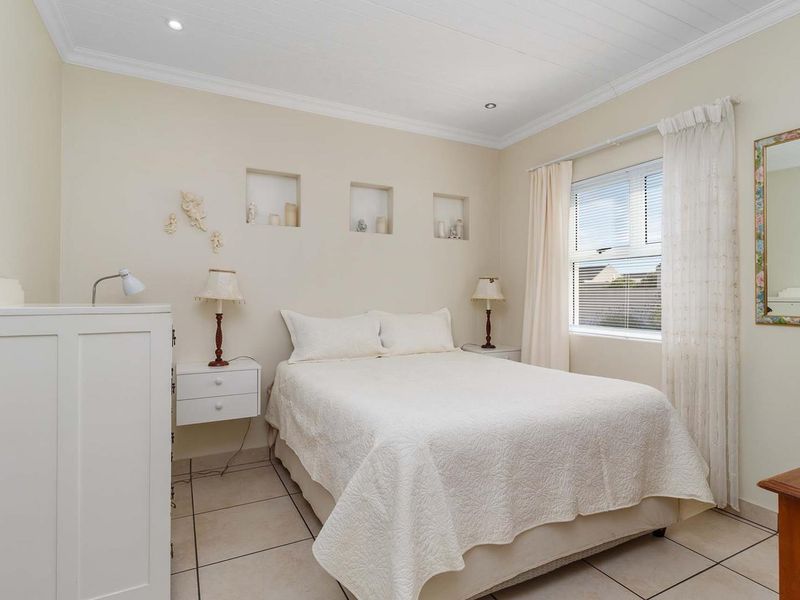 A well-maintained bedroom featuring tiled flooring, recessed wall niches, crown molding, and recessed downlighting.