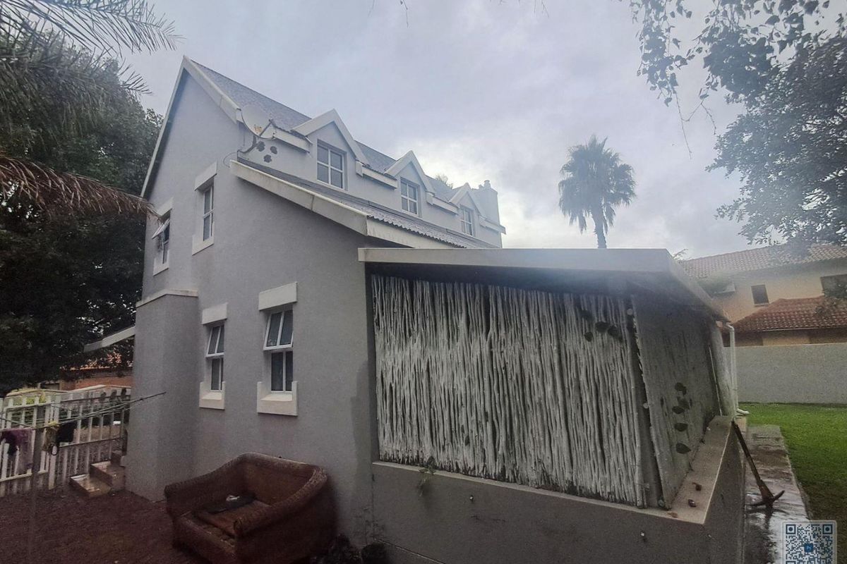 Side elevation of a multi-story residential property featuring a covered patio area with timber screening and multiple dormer windows.