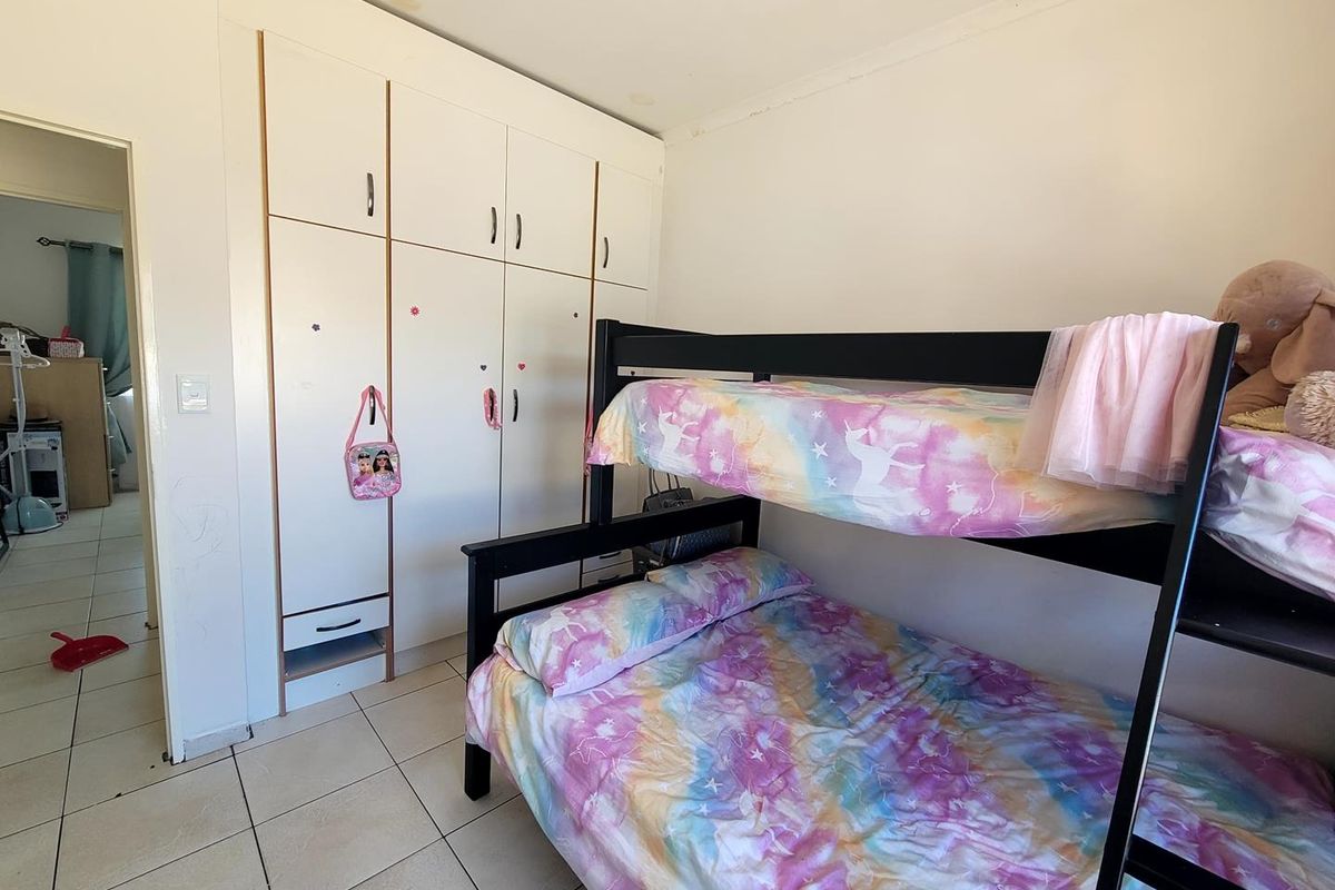 A bedroom featuring built-in white cabinetry and tiled flooring, providing functional storage space.