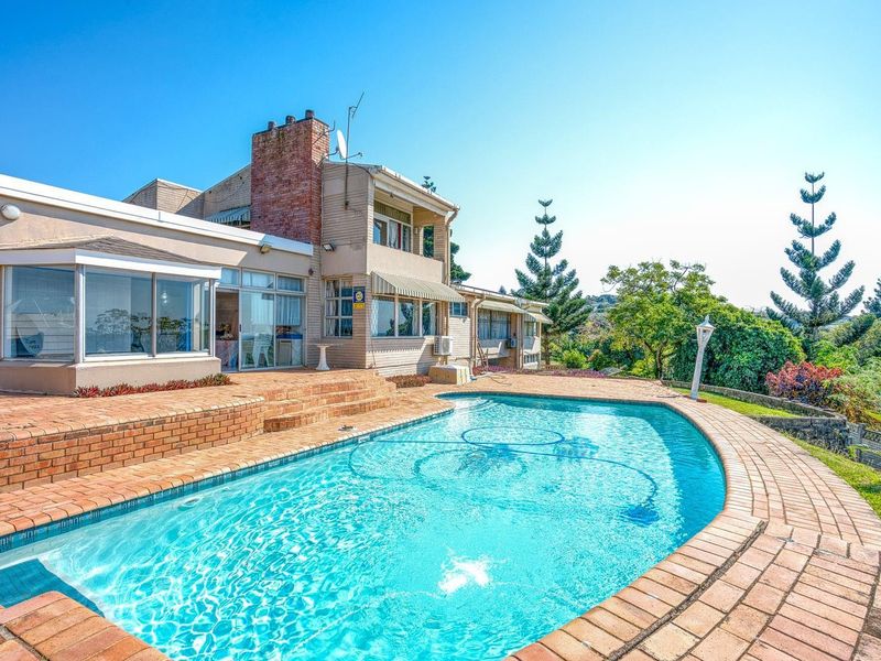 Rear exterior view featuring a swimming pool with brick paving, a sunroom extension, and a multi-level house structure with a brick chimney.