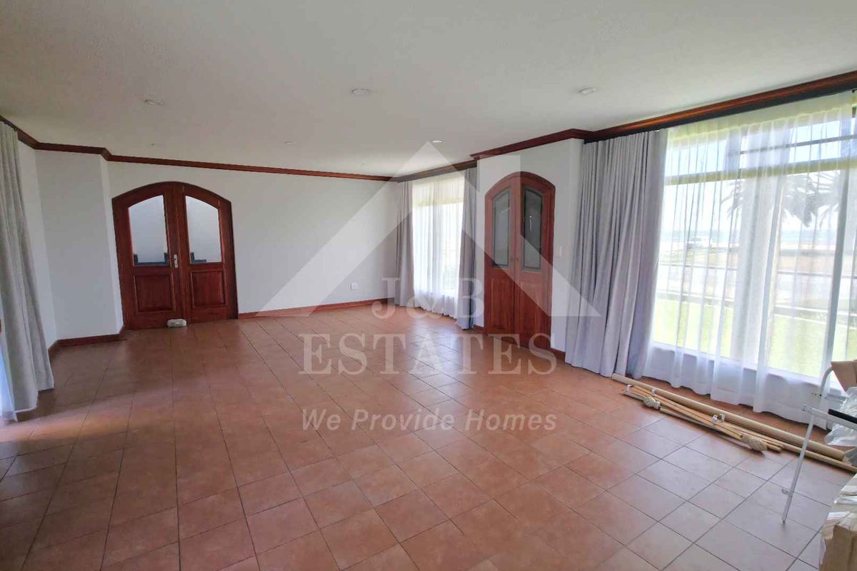 Spacious living area featuring tiled flooring, recessed lighting, and distinctive arch-top wooden double doors, offering a bright and open layout.