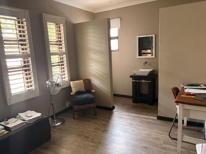 Bedroom featuring laminate flooring, plantation shutters, and a semi-open ensuite area with a modern vessel sink and vanity.