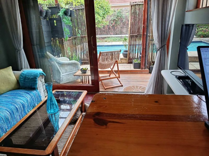 Living room featuring large sliding glass doors opening onto a wooden deck with a swimming pool view.