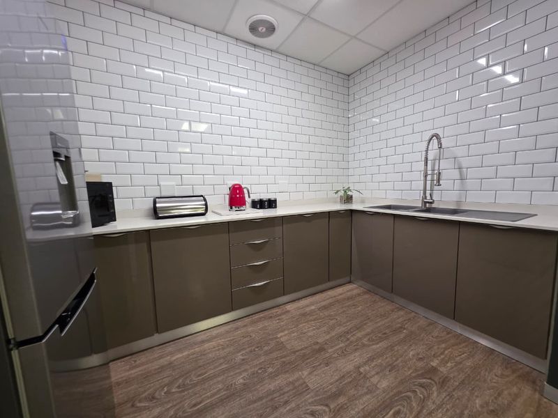 Modern kitchen featuring sleek cabinetry, white subway tile backsplash, composite countertops, and a professional-style gooseneck faucet with wood-look flooring.