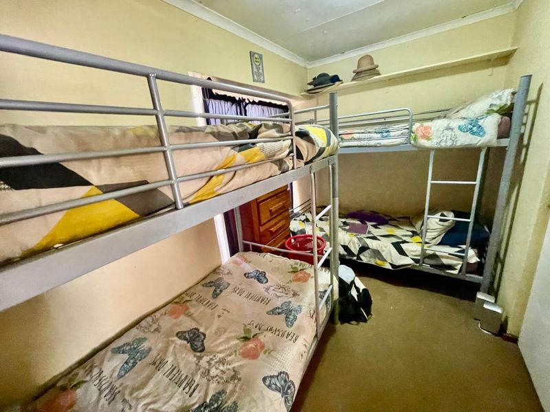 A compact bedroom featuring built-in shelving and space for multiple beds, requiring cosmetic updates to improve the overall finish and appeal.