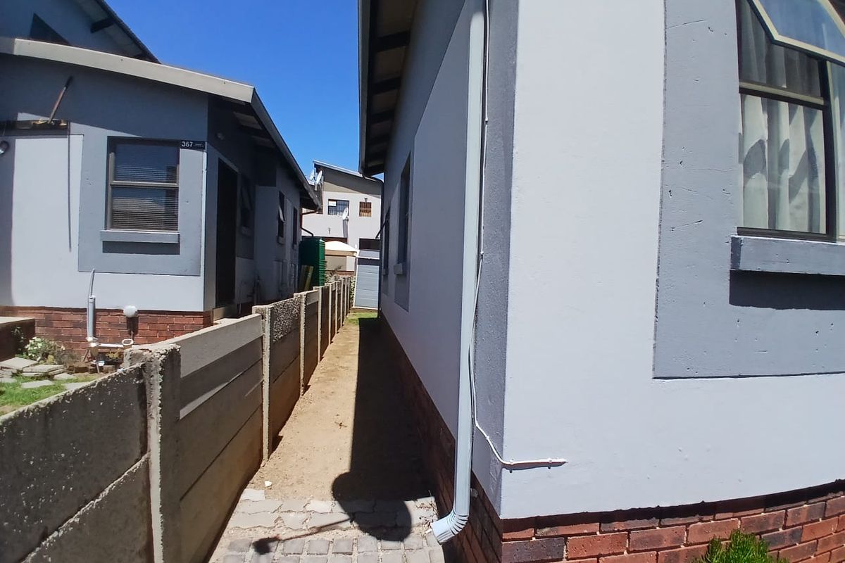 Side passage of the townhouse featuring a paved walkway, precast concrete boundary wall, and exterior brick plinth detailing.