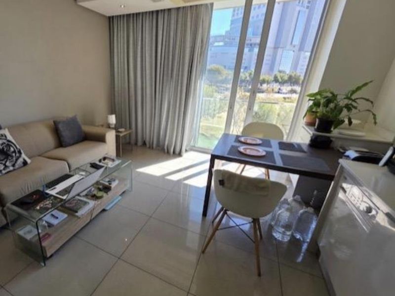 Modern open-plan living and dining area featuring large floor-to-ceiling glass doors, tiled flooring, and integrated ducted air conditioning.