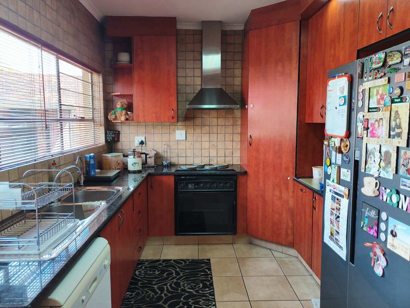 A functional kitchen featuring warm-toned cabinetry, granite countertops, a built-in oven with extractor fan, and a double basin sink with tiled backsplash.
