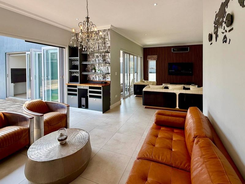 Spacious living area featuring a built-in bar, modern tiled flooring, and large bi-fold doors that open to an outdoor patio space.