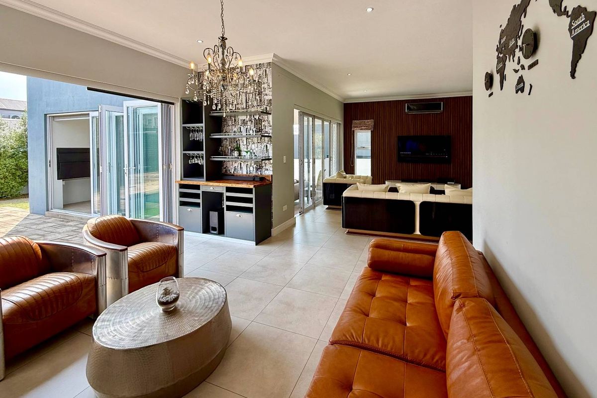 Spacious living area featuring a built-in bar, modern tiled flooring, and large bi-fold doors that open to an outdoor patio space.