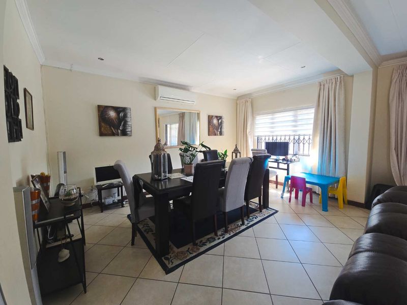 Spacious dining area featuring tiled flooring, recessed downlighting, and a wall-mounted split-system air conditioner, providing a functional and comfortable space for family meals.