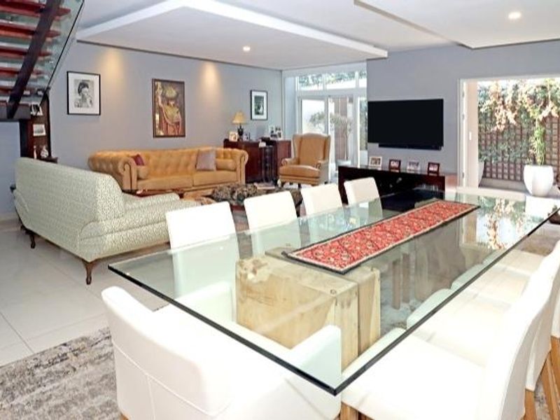 Spacious open-plan living and dining area featuring a modern floating staircase, recessed ceiling details, and large sliding glass doors leading to the outdoor space.