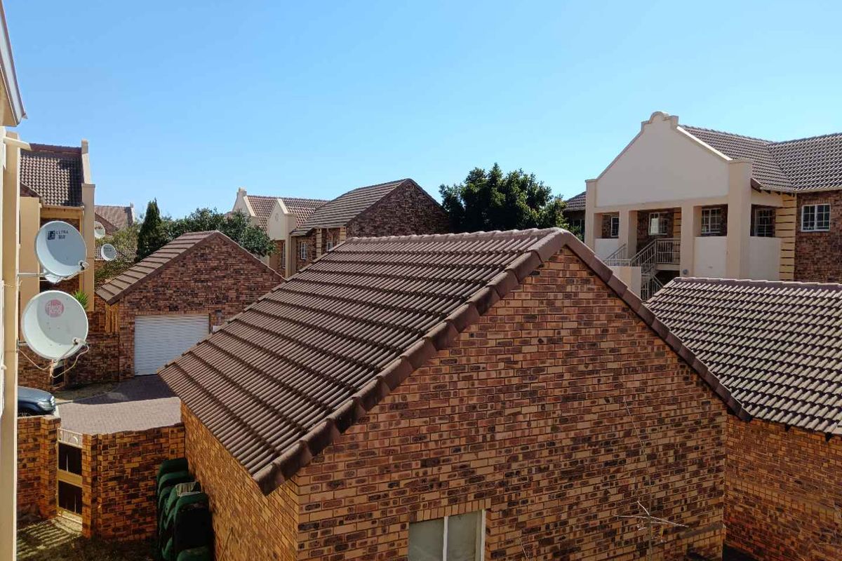 An elevated view of the residential complex featuring facebrick buildings with tiled roofs and satellite dish installations.