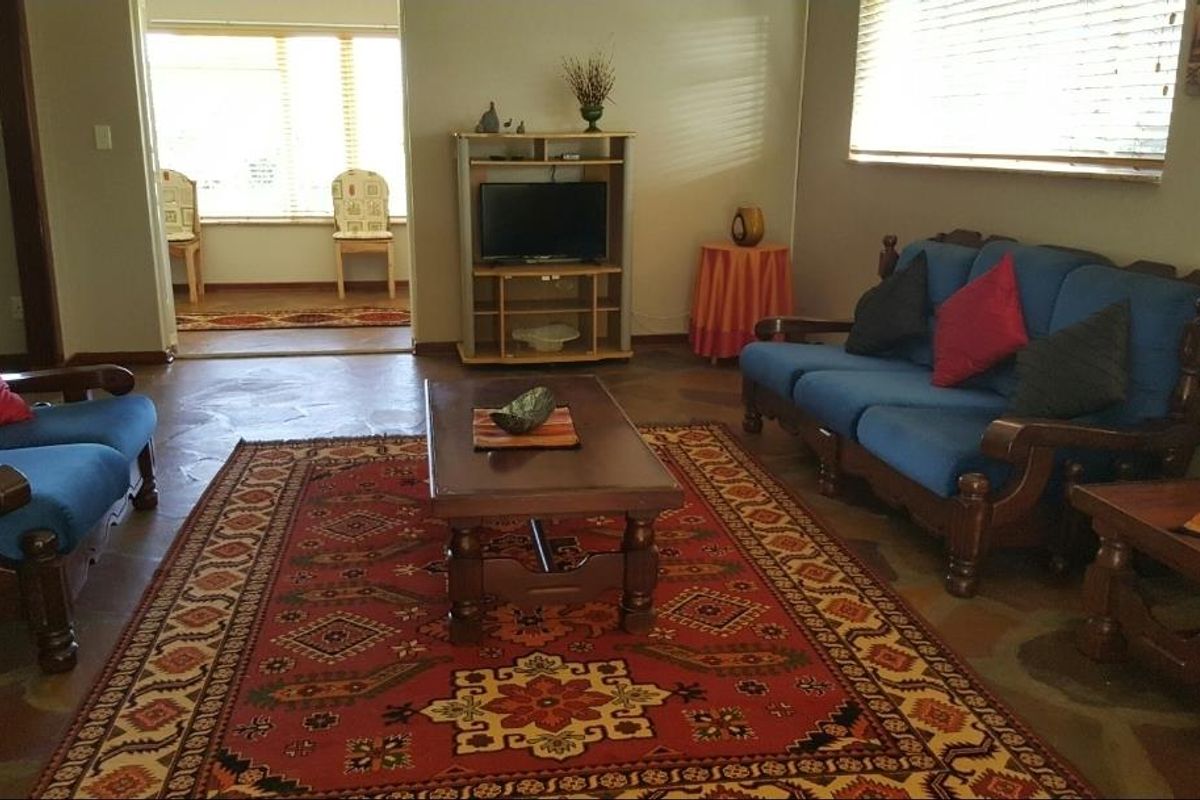A spacious living room featuring tiled flooring and large windows with blinds, providing a comfortable and functional area for relaxation.