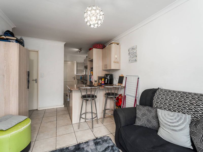 Open plan living area featuring tiled flooring and a compact kitchen with granite countertops and a breakfast bar.