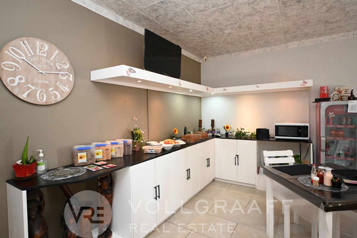 A functional kitchen area featuring white cabinetry, dark countertops, integrated lighting, and a textured ceiling finish.