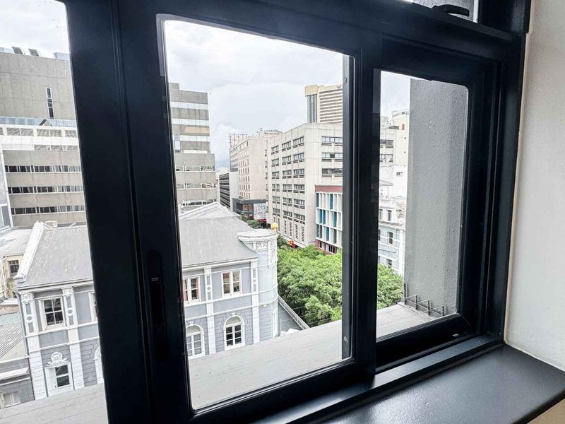 A view of the surrounding city buildings captured through a modern black aluminium window frame.
